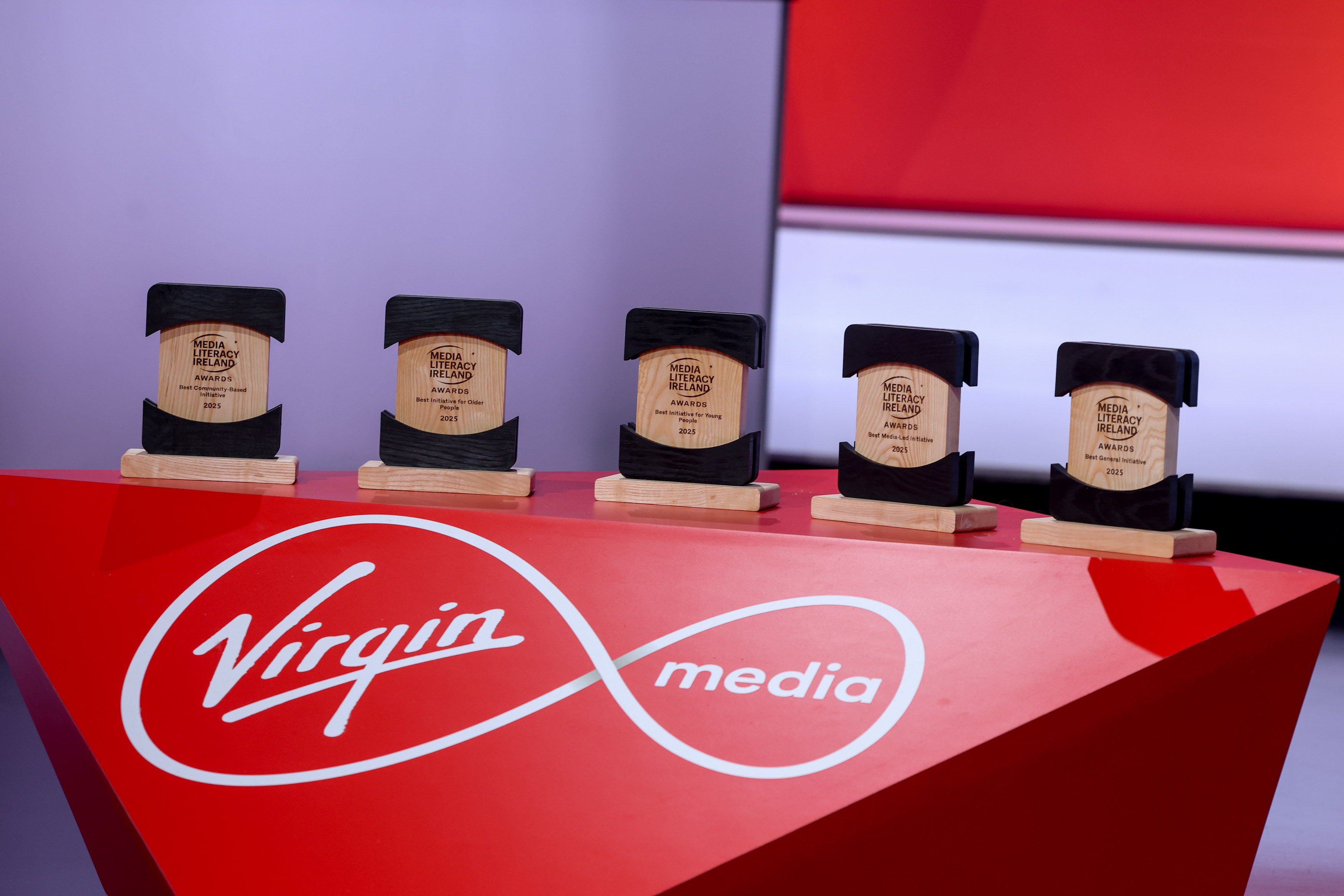 Five Media Literacy Ireland awards from left-to-right on a red table with Virgin media written on the front of the table in white